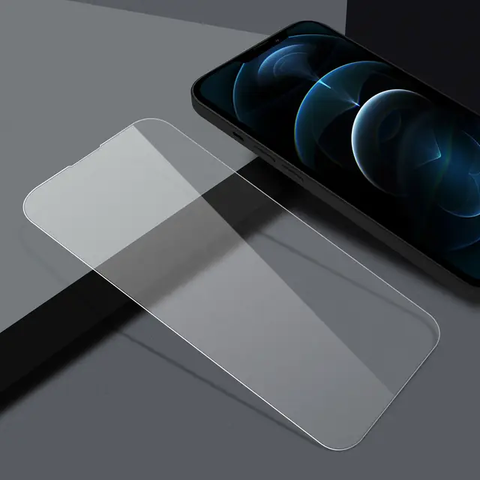 Das HandyOase Panzerglas iPhone 3er-Set liegt neben einem schwarzen Smartphone auf einer grau-schwarzen Oberfläche.