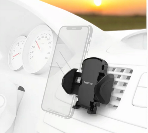Eine Hama Universal Kfz-Halterung (Schwarz) Lüftungsgitter von HandyOase ist an einer Autolüftungsöffnung befestigt und hält fest den Umriss eines durchscheinenden Smartphones, hinter dem ein verschwommener Sonnenuntergang sichtbar ist.